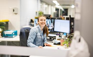 Image: Staff sitting at computer smiling through glass window