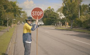 Image: man on road holding a stop sign