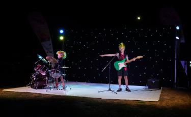 Image: 2 boys on stage with guitar and drums
