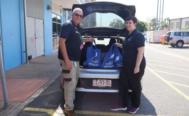 Two library staff members loading Library to You bags into a vehicle.
