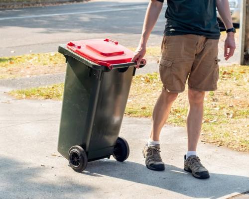 Image: Man walking rubbish bin