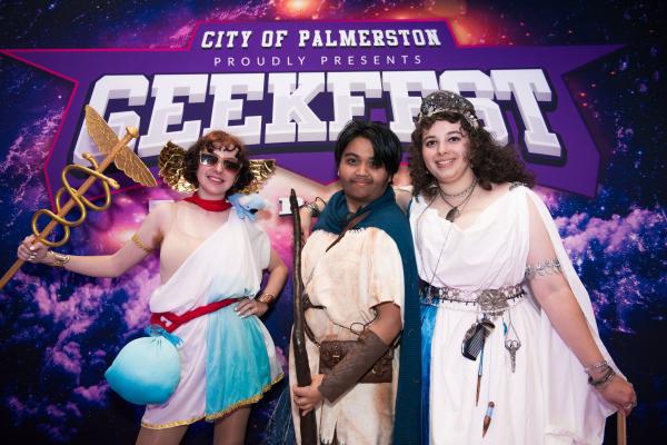 Image: 3 youth dressed up in front of the Geekfest Top End photodrop