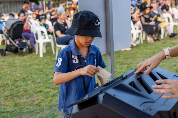 Image: young boy putting card into barrel 
