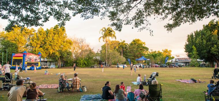 Image: people sititng on grass with sun setting 