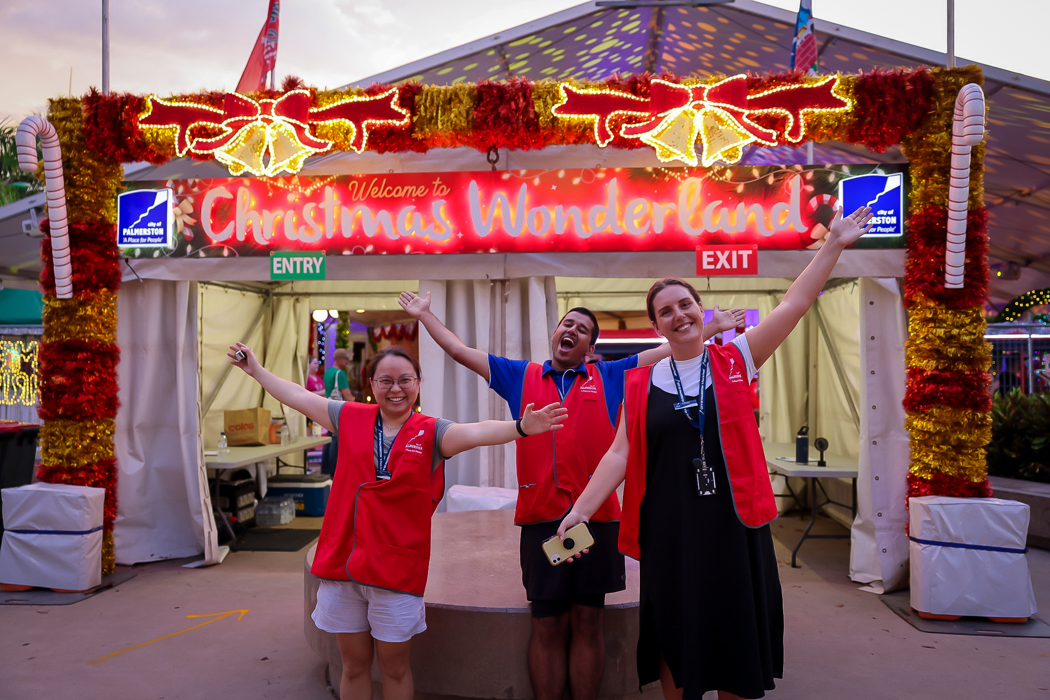 Staff in red vests at the front of Christmas Wonderland event with their arms outreached